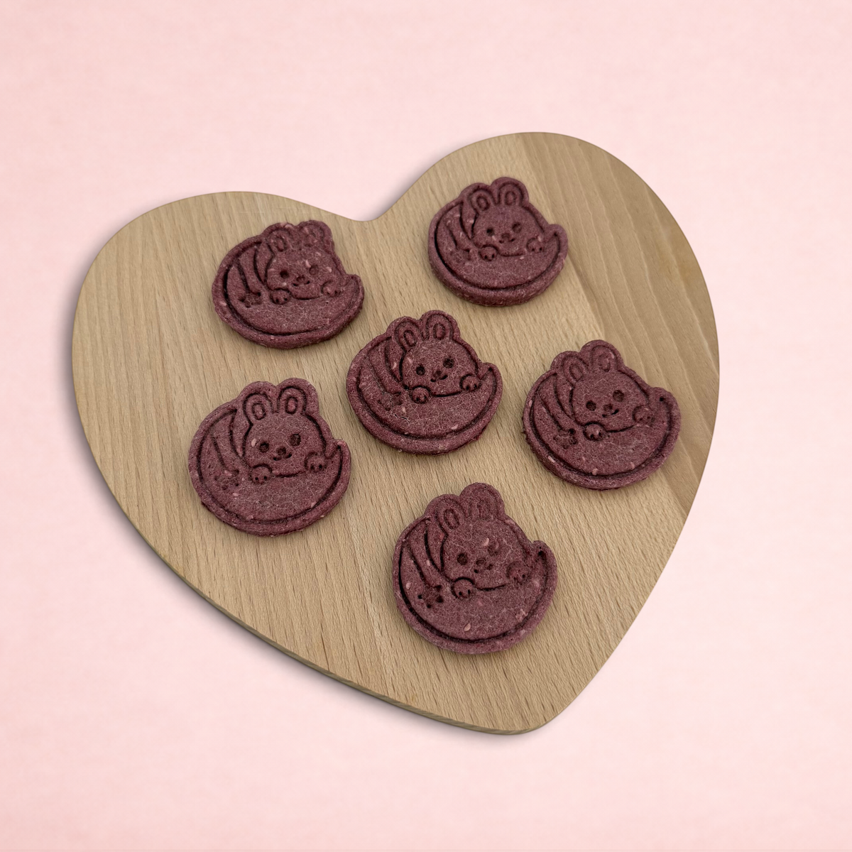 Darling Bun Shop handmade raspberry and oat bunny-shaped treats for small animals on a wooden heart board
