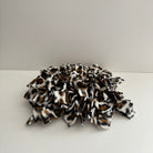 A snuffle mat with a snow leopard print design, made of fabric with a textured surface, intended for small pets to forage and find treats.