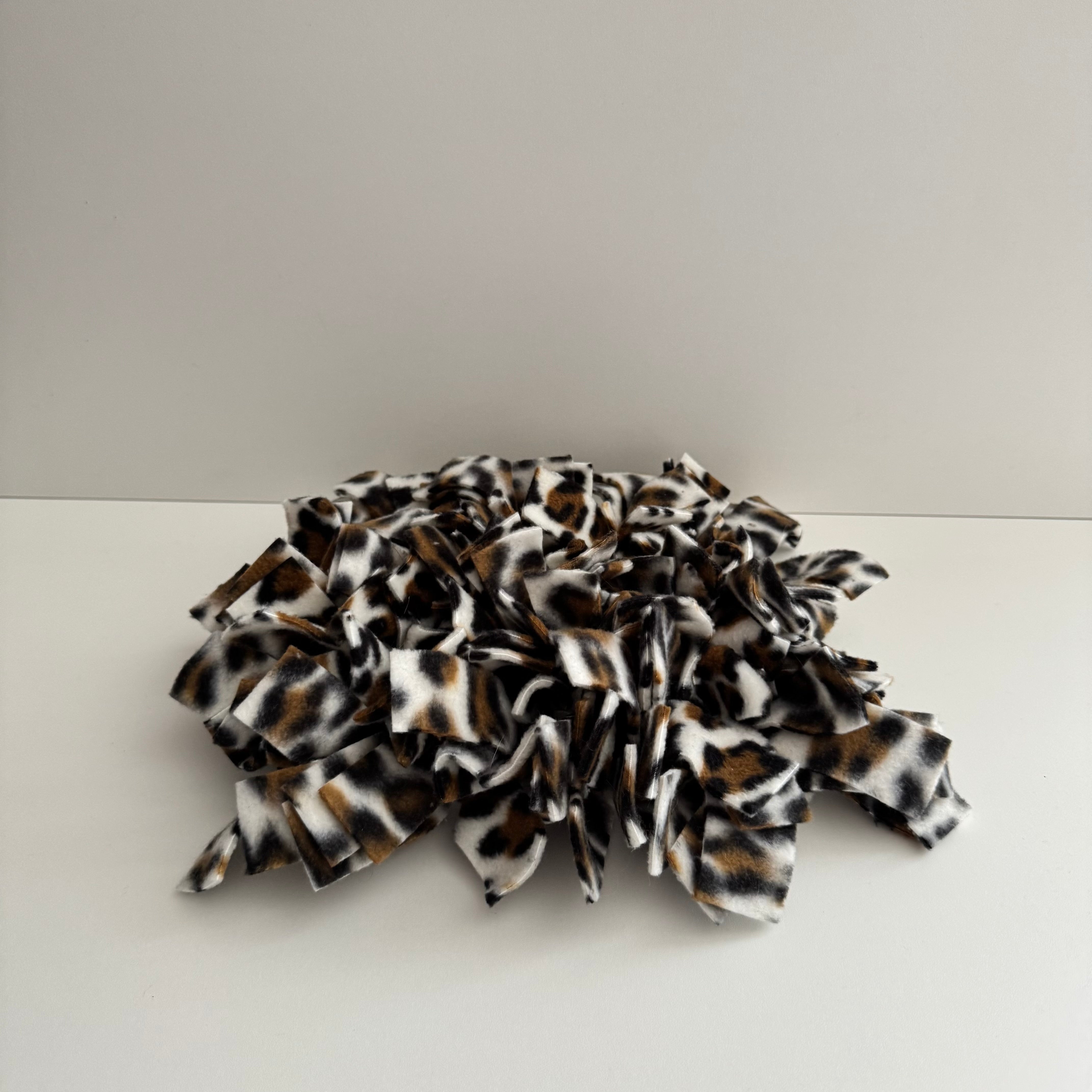 A snuffle mat with a snow leopard print design, made of fabric with a textured surface, intended for small pets to forage and find treats.