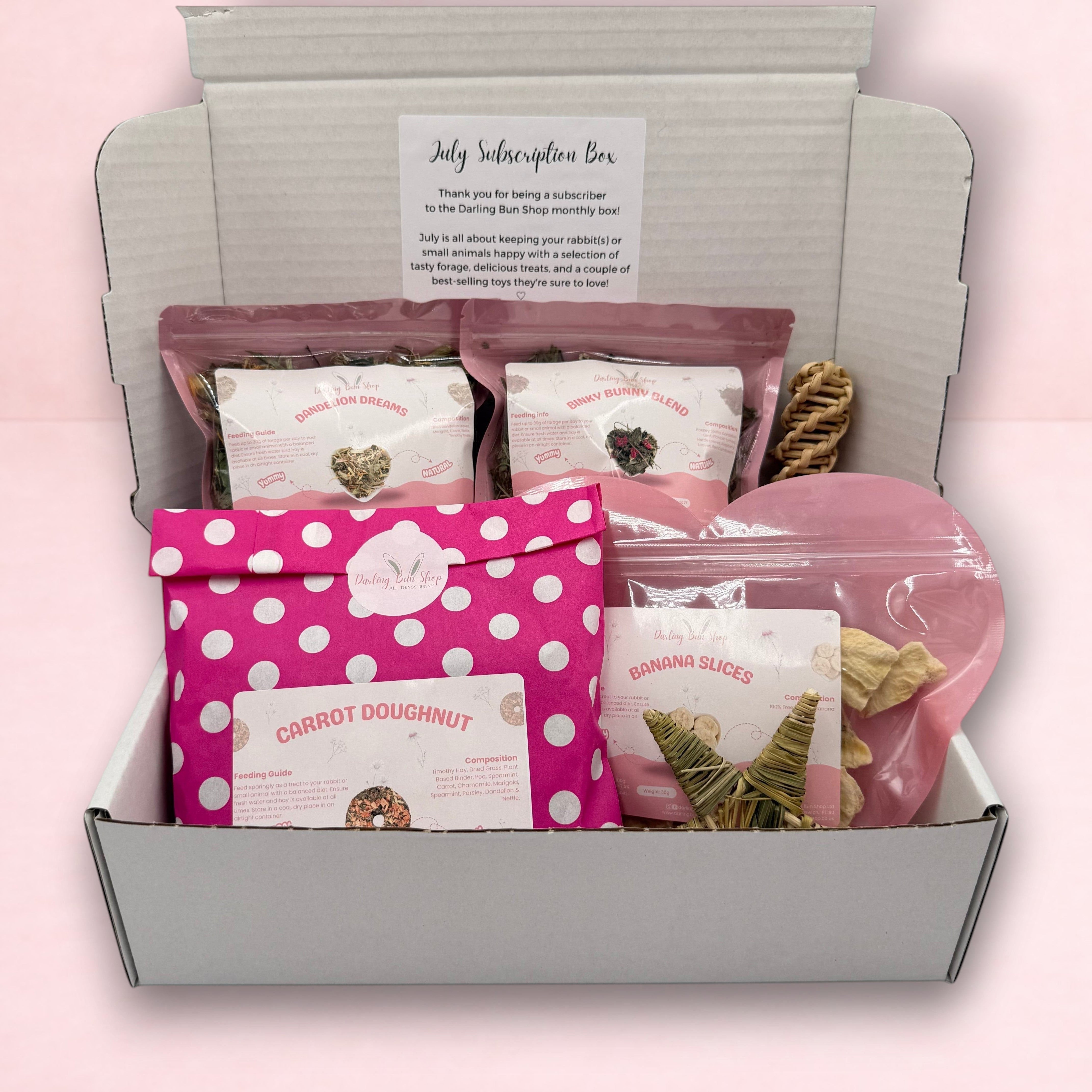 Darling Bun Shop July subscription box for rabbits containing assorted natural forage, treats, and enrichment toys.