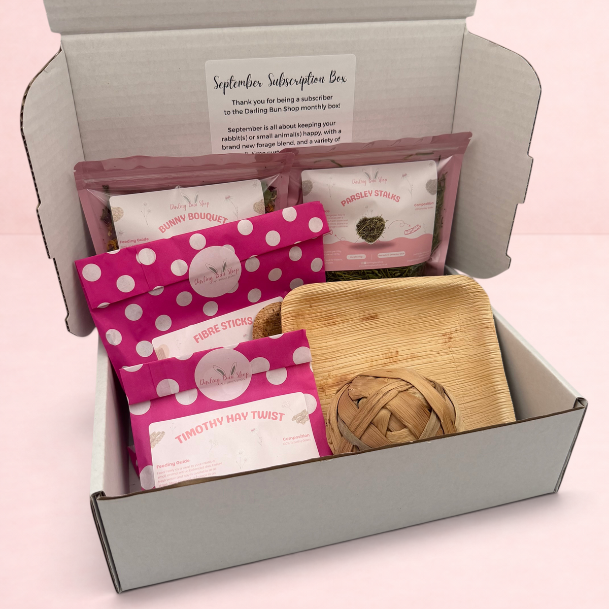 Darling Bun Shop September subscription box for rabbits containing forage treats, fibre sticks, and a wooden toy.