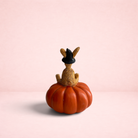 Darling Bun Shop handmade witch rabbit ornament wearing a black hat, sitting on an orange pumpkin for Halloween decor.