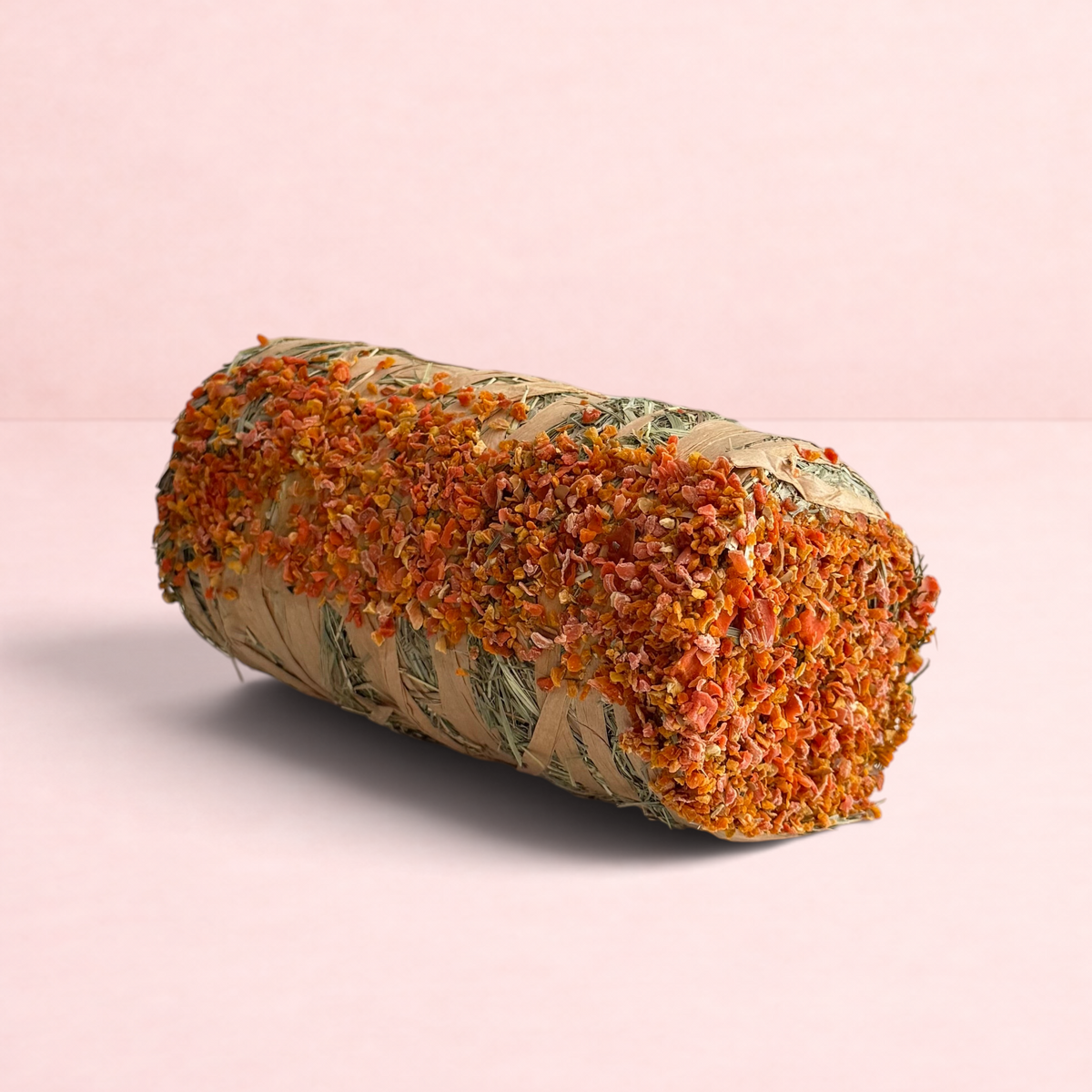 Darling Bun Shop hay bale treat for small pets, featuring dried pumpkin and carrot pieces on a cylindrical hay roll.