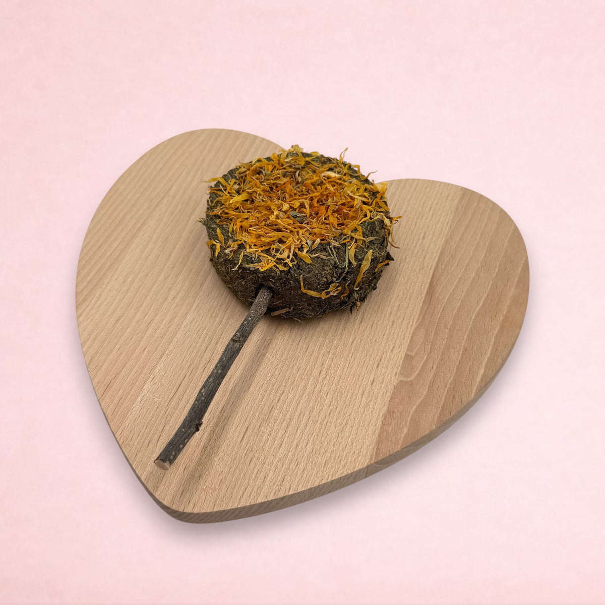 Darling Bun Shop hay-based marigold lolly treat for small animals with an apple wood stick on a heart-shaped board