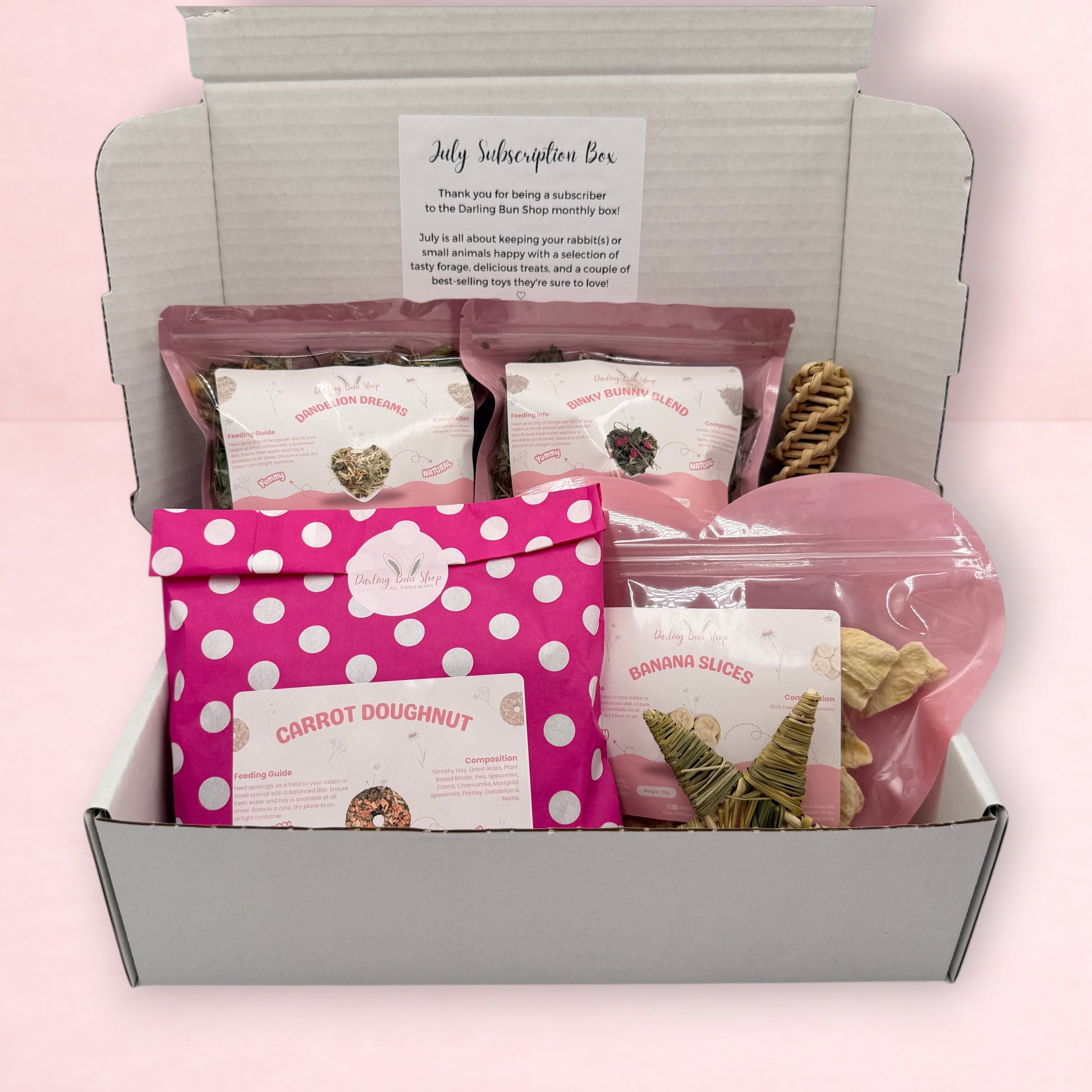 Darling Bun Shop July subscription box for rabbits containing natural forage, dried banana treats, and chew toys.