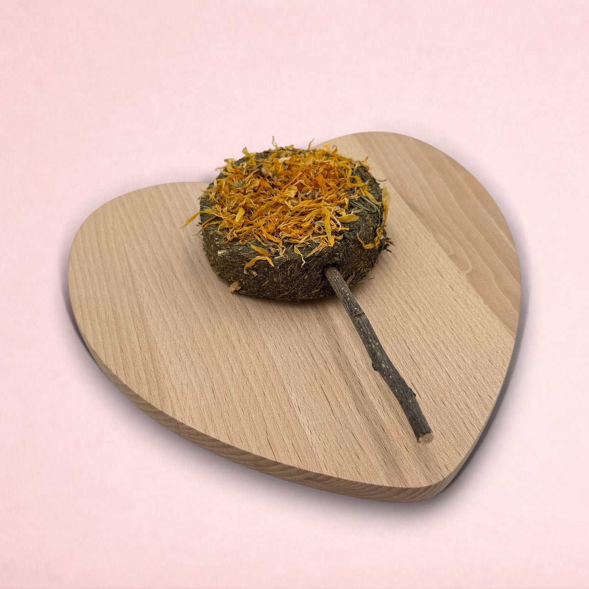 Darling Bun Shop hay-based marigold lolly treat with apple wood stick for small animals on a heart-shaped board